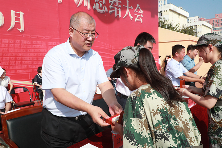 校党委书记刘双耀向新生代表赠送刻有“精诚仁朴”校训的蓝田玉纪念章