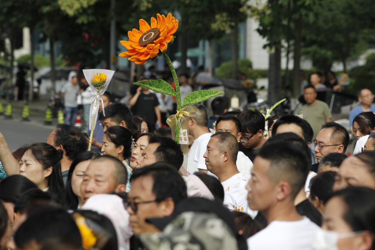 12，6月8日下午，在西安高级中学考点，一位家长高举“向日葵”在考场外迎接考生。当日，全国部分地区2024年高考结束。（梁萌摄）