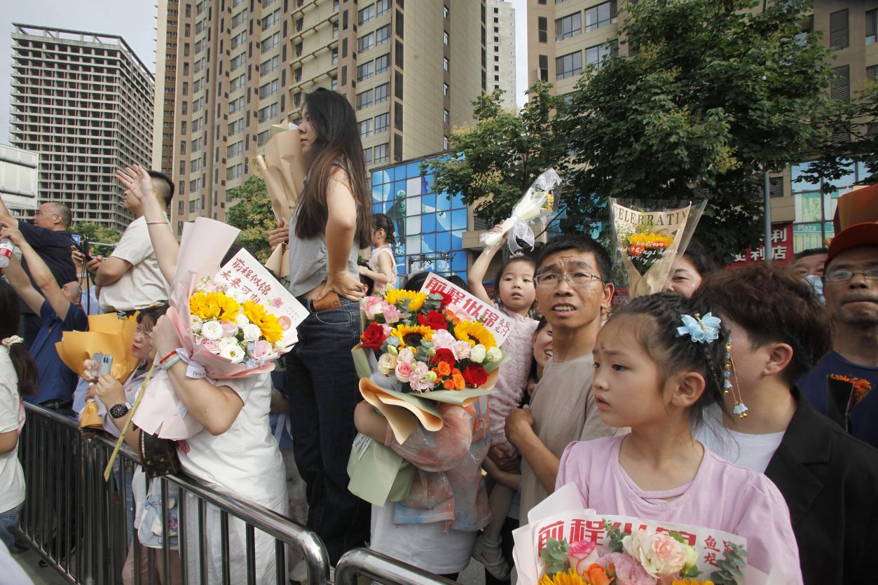20，6月8日下午，在西安高级中学考点，家长们手捧花束翘首以盼。当日，全国部分地区2024年高考结束。（梁萌摄）